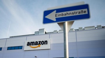 Ein Einbahnstraßenschild ist vor dem Amazon Schriftzug am Logistikzentrum zu sehen. Foto: Philipp Schulze/dpa