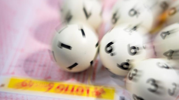 Lotto-Kugeln liegen auf einem Lottoschein. Foto: Tom Weller/dpa/Archiv/Symbolbild