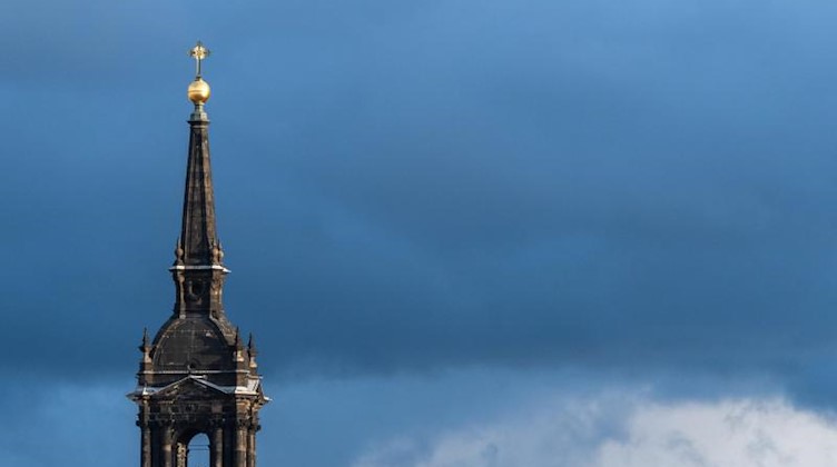 Eine Kirchturm vor dunklen Wolken. Foto: Robert Michael/dpa-Zentralbild/ZB/Symbolbild