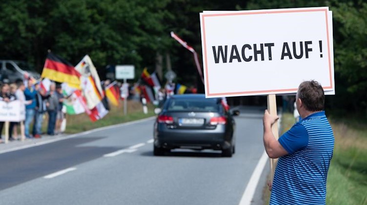 Ein Demonstrant hält an der B96 ein Schild mit der Aufschrift «Wacht auf». Foto: Sebastian Kahnert/dpa-Zentralbild/dpa/Archivbild