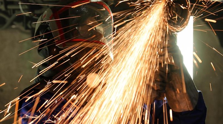 Ein Mitarbeiter eines Maschinenbauunternehmens schneidet Metallteile. Foto: Jan Woitas/dpa-Zentralbild/dpa/Illustration
