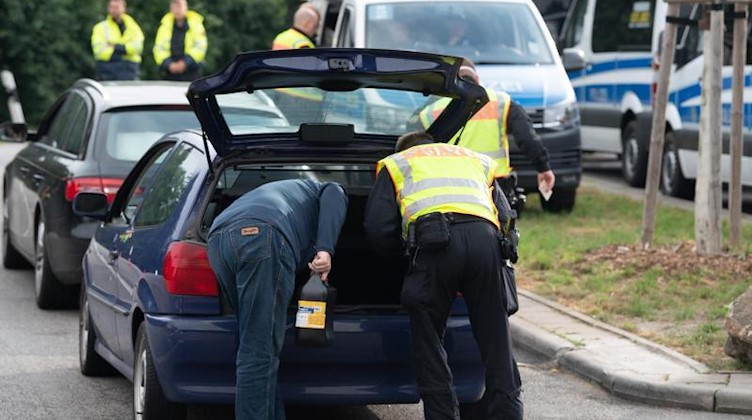 Ein Polizist inspiziert den Kofferraum eines Fahrzeugs. Foto: Sebastian Kahnert/dpa-Zentralbild/dpa