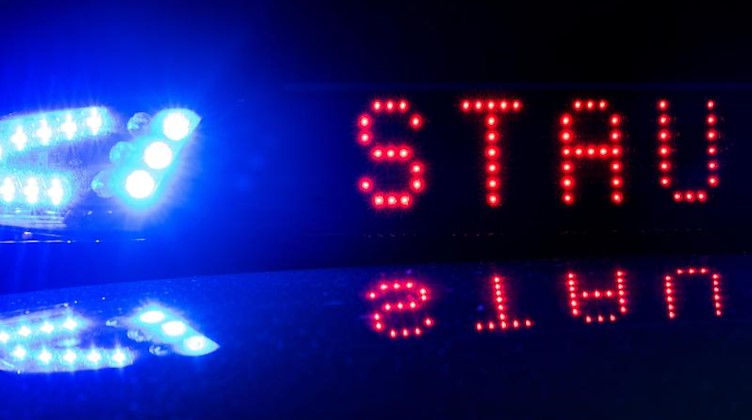 Das Blaulicht auf einem Polizeifahrzeug der leuchtet, während sich das Display mit dem Wort «Stau» spiegelt. Foto: Monika Skolimowska/zb/dpa/Symbolbild