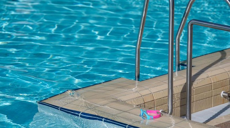 Eine Schwimmbrille liegt am Rande eines Schwimmbeckens. Foto: Lino Mirgeler/dpa/Symbolbild