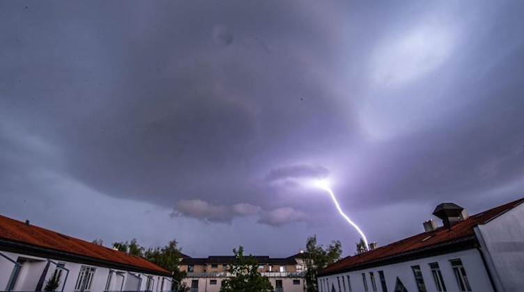 Ein Blitz schlägt in der Ferne ein. Foto: Lino Mirgeler/dpa/Archivbild