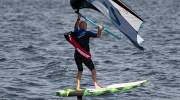 Ein Wing-Surfer reitet auf den Wellen. Foto: Paul Zinken/dpa/Archiv