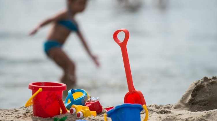 Sandspielzeug steht am Strand eines Badesees. Foto: Sophia Kembowski/dpa/Archivbild