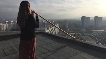 Die Alphornistin Anna Katharina Schumann probt für das Konzert «Himmel über Prohlis». Foto: --/Dresdner Sinfoniker/Therese Menzel/dpa/Archivbild