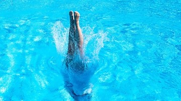Eine Frau macht einen Kopfsprung in das Becken eines Freibads. Foto: Sebastian Gollnow/dpa/Symbolbild
