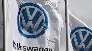 Flaggen mit dem VW-Logo wehen vor dem Werk von Volkswagen. Foto: Hendrik Schmidt/dpa-Zentralbild/dpa/Archivbild
