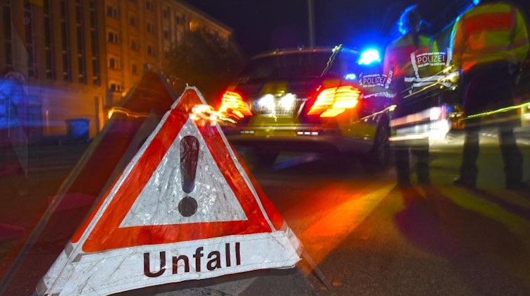Ein Polizeifahrzeug steht mit Blaulicht auf der Straße. Daneben steht ein Warndreieck mit dem Schriftzug «Unfall». Foto: Patrick Seeger/dpa/symbol