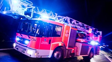 Ein Drehleiterwagen der Feuerwehr fährt mit Blaulicht an einer Unfallstelle vorbei. Foto: Marcel Kusch/dpa/Illustration