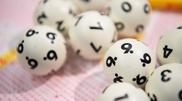 Lotto-Kugeln liegen auf einem Lottoschein. Foto: Tom Weller/dpa/Archiv