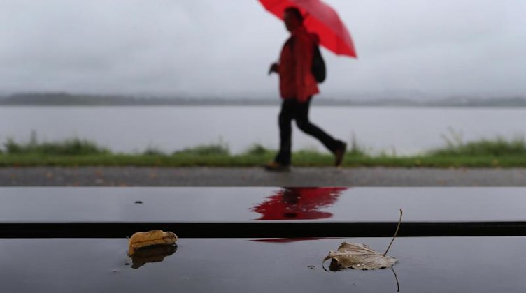 Ein Spaziergänger geht im Regen an einer Uferpromenade entlang. Foto: Karl-Josef Hildenbrand/dpa/Symbolbild