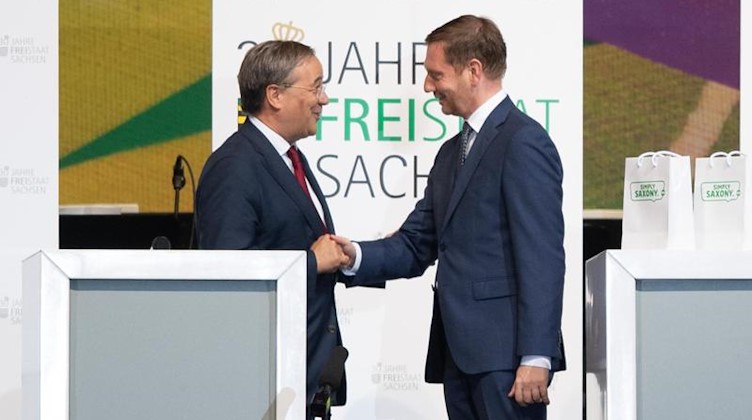 Die Ministerpräsidenten Armin Laschet (l) und Michael Kretschmer reichen sich die Hände. Foto: Sebastian Kahnert/dpa-Zentralbild/dpa