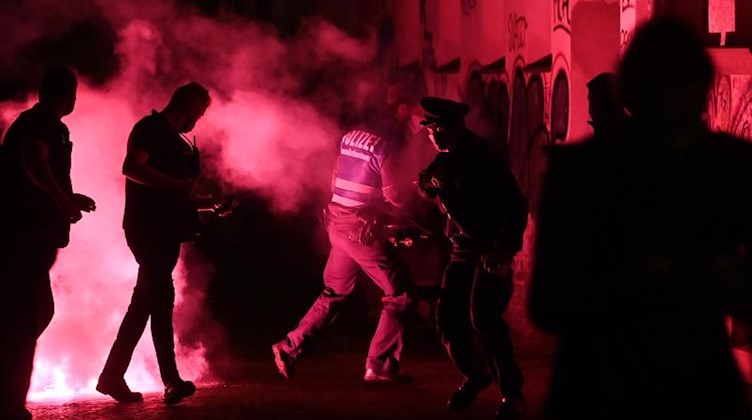 Polizisten laufen von der Stelle weg, an der zuvor eine rote Pyro-Fackel explodiert war. Foto: Hendrik Schmidt/dpa-Zentralbild/dpa