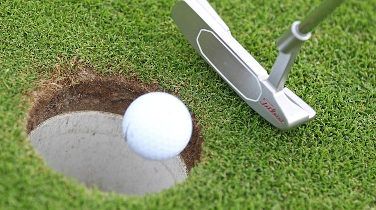 Eine Golfspielerin locht mit einem Schlag den Golfball ein. Foto: Jan Woitas/dpa-Zentralbild/dpa/Symbolbild