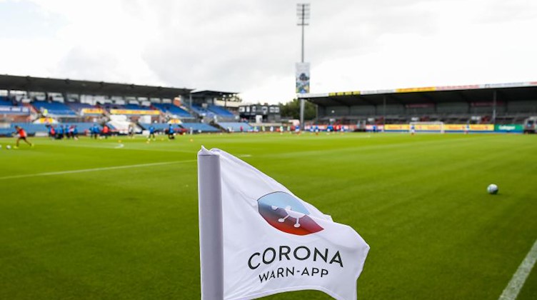 Eine Eckfahne im Fußballstadion mit Corona-Logo. Foto: Gregor Fischer/dpa/Archivbild