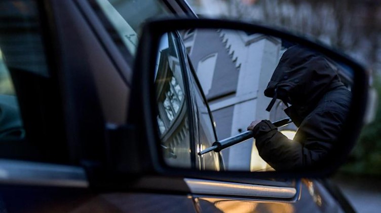 Ein Mann versucht eine Autotür mit einer Metallstange aufzubrechen. Foto: Axel Heimken/dpa/Illustration