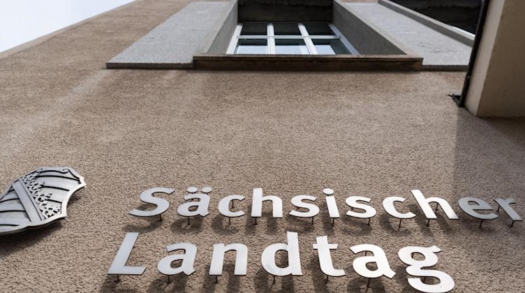 Ein Sachsen-Wappen und der Schriftzug Sächsischer Landtag sind an der Fassade des Landtages angebracht. Foto: Robert Michael/dpa-Zentralbild/dpa/Archiv