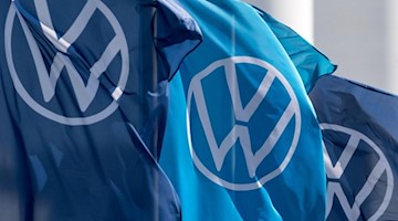 Fahnen mit dem VW-Logo wehen im Fahrzeugwerk von Volkswagen. Foto: Hendrik Schmidt/dpa-Zentralbild/dpa