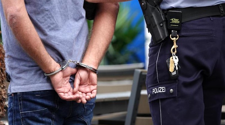 Ein Mann wird in Handschellen von der Polizei abgeführt. Foto: Johannes Neudecker/dpa/Symbolbild