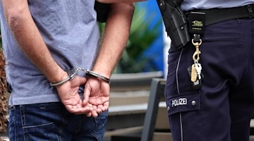 Ein Mann wird in Handschellen von der Polizei abgeführt. Foto: Johannes Neudecker/dpa/Symbolbild