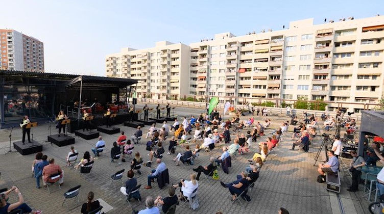 Besucher sitzen während eines Konzerts auf einem Parkhaus ium Stadtteil Prohlis. Foto: Sebastian Kahnert/dpa-Zentralbild/dpa