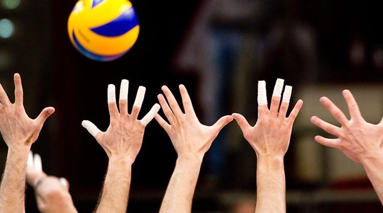 Hände greifen nach einem Volleyball. Foto: picture alliance / dpa/Symbolbild