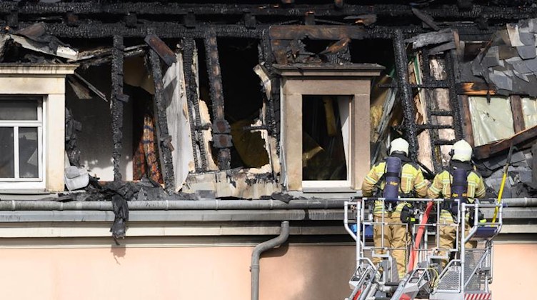 Einsatzkräfte der Feuerwehr begutachten von einer Drehleiter aus den Dachstuhl nach einem Brand in einem Mehrfamilienhaus. Foto: Sebastian Kahnert/dpa-Zentralbild/dpa