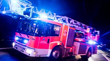 Ein Drehleiterwagen der Feuerwehr fährt mit Blaulicht an einer Unfallstelle vorbei. Foto: Marcel Kusch/dpa/Illustration