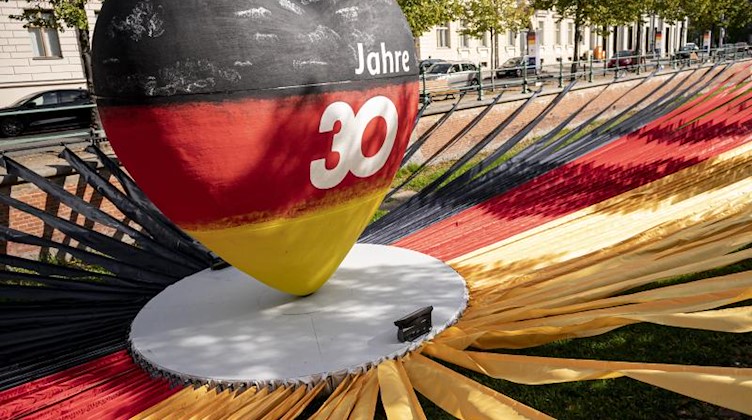 Ein Herz in Farben der Deutschen Flagge mit der Aufschrift «30 Jahre» steht im Sonnenlicht. Foto: Fabian Sommer/dpa/Symbol
