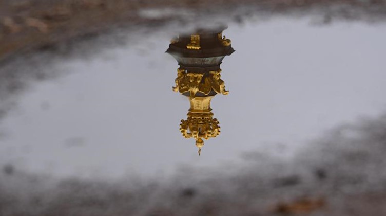 Das Kronentor auf dem Dresdner Zwinger spiegelt sich in einer Pfütze. Foto: Robert Michael/dpa-Zentralbild/ZB/Symbolbild