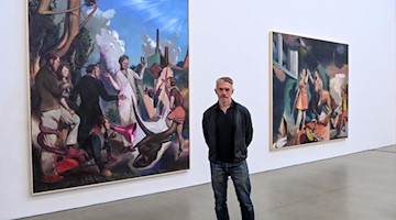 Neo Rauch in der Galerie «Eigen + Art» zwischen seinen Arbeiten «Die Wurzel» und «Handlauf» (l-r). Foto: Hendrik Schmidt/dpa-Zentralbild/dpa