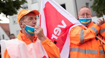 Demonstranten der Entsorgungsbetriebe halten bei einem Protest eine Verdi-Fahne in der Hand. Foto: Tom Weller/dpa/Symbolbild