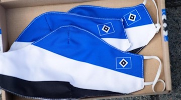 Drei Mund-Nasen-Schutzmasken in den Farben des Hamburger SV. Foto: Christian Charisius/dpa/Archivbild