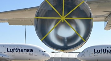 Zwei Airbus A380-800 der Lufthansa hinter einem A380, an dem ein Triebwerk ausgebaut worden war. Foto: Arne Dedert/dpa Pool/dpa/Archivbild