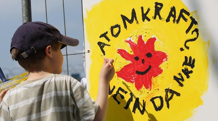 Ein Schüler malt das Anti-AKW-Symbol «Atomkraft - Nein Danke» auf eine Wand. Foto: picture alliance / dpa/Archivbild