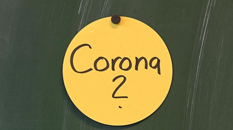 Das Wort "Corona?" ist auf einem Papierschild geschrieben, das an der Tafel angebracht ist. Foto: Felix Kästle/dpa/Symbol