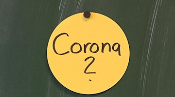 Das Wort "Corona?" ist auf einem Papierschild geschrieben, das an der Tafel angebracht ist. Foto: Felix Kästle/dpa/Symbol