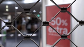 Ein Schild mit der Aufschrift "50% extra" ist kurz nach Ladenschluss an einem geschlossenen Geschäft zu sehen. Foto: Sven Hoppe/dpa/Symbol