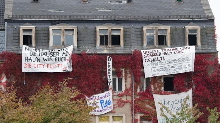 Transparente von Aktivisten hängen an den Fenstern eines leerstehenden Wohnhauses. Foto: Sebastian Kahnert/dpa-Zentralbild/dpa