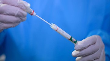 Ein Arzt hält einen Coronavirus-Test in den Händen. Foto: Robert Michael/dpa-Zentralbild/dpa/Symbolbild