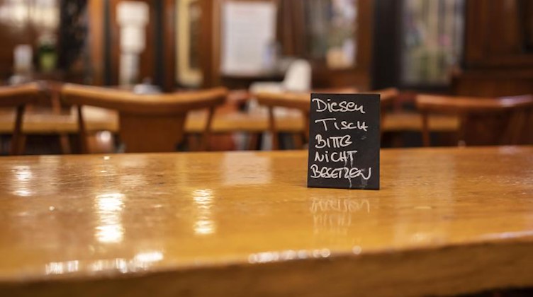 Eine Tafel mit der Aufschrift «Diesen Tisch bitte nicht besetzen» steht auf einem der Tische in einem Restaurant. Foto: Frank Rumpenhorst/dpa/Symbolbild