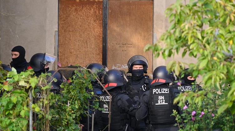 Polizisten stehen während einer Durchsuchung vor einem besetzten Haus. Foto: Sebastian Kahnert/dpa-Zentralbild/dpa