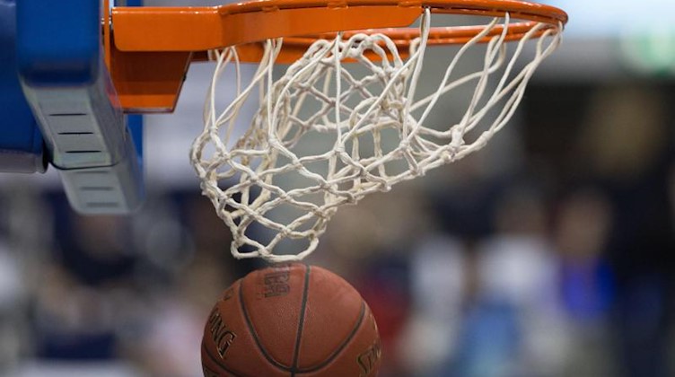 Ein Basketball fällt durch das Netz vom Basketballkorb. Foto: Lukas Schulze/dpa/Symbolbild