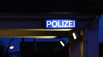 Ein Schild mit der Aufschrift «Polizei» leuchtet am Eingangsbereich der Polizeistation. Foto: Silas Stein/dpa/Symbolbild