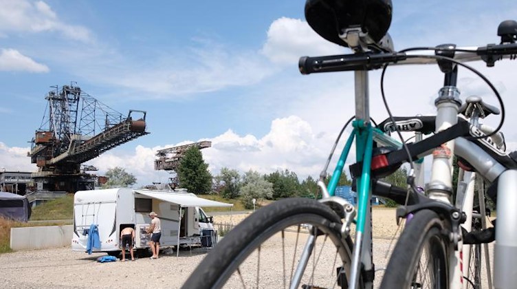 Fahrräder und ein Wohnmobil stehen in Ferropolis vor ausgedienter Bergbautechnik. Foto: Sebastian Willnow/dpa-Zentralbild/dpa/Archivbild
