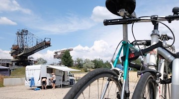 Fahrräder und ein Wohnmobil stehen in Ferropolis vor ausgedienter Bergbautechnik. Foto: Sebastian Willnow/dpa-Zentralbild/dpa/Archivbild