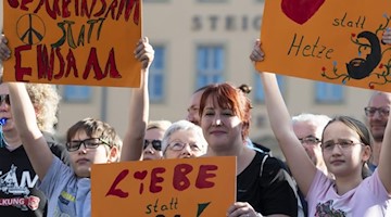 Teilnehmer einer Kundgebung halten Plakate. Foto: Matthias Rietschel/dpa-Zentralbild/dpa/Archivbild